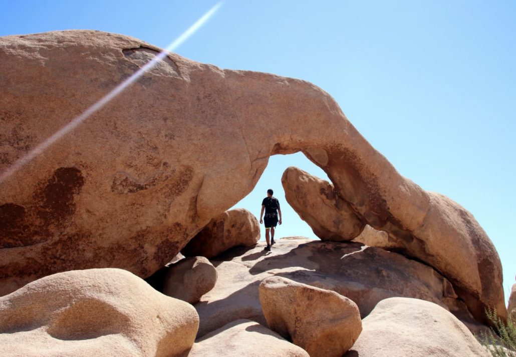 Person exploring the Arch Rock, in the Joshua Tree National Park, California, USA.