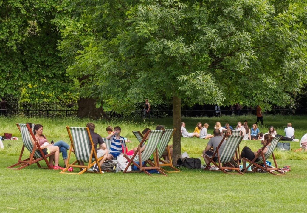 People sitting on deck chairs in Green Park, London, UK.