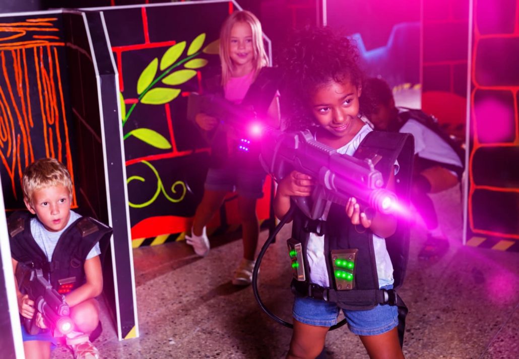 Three kids, two girls and one boy, playing laser tag.