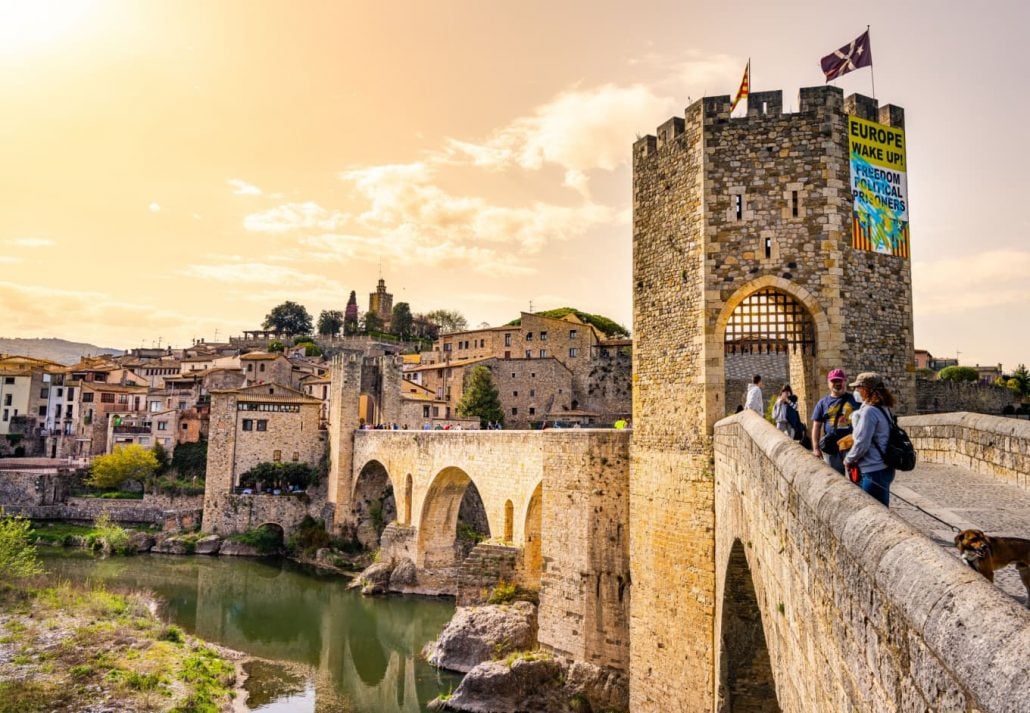 Tourists entering via the bridge over the river Fluvia in the medieval village de Besalú, Girona, Catalonia, Spain.