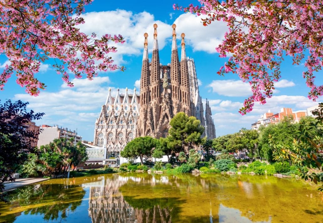 Barcelona's Sagrada Familia surrounded by blooming trees during spring.