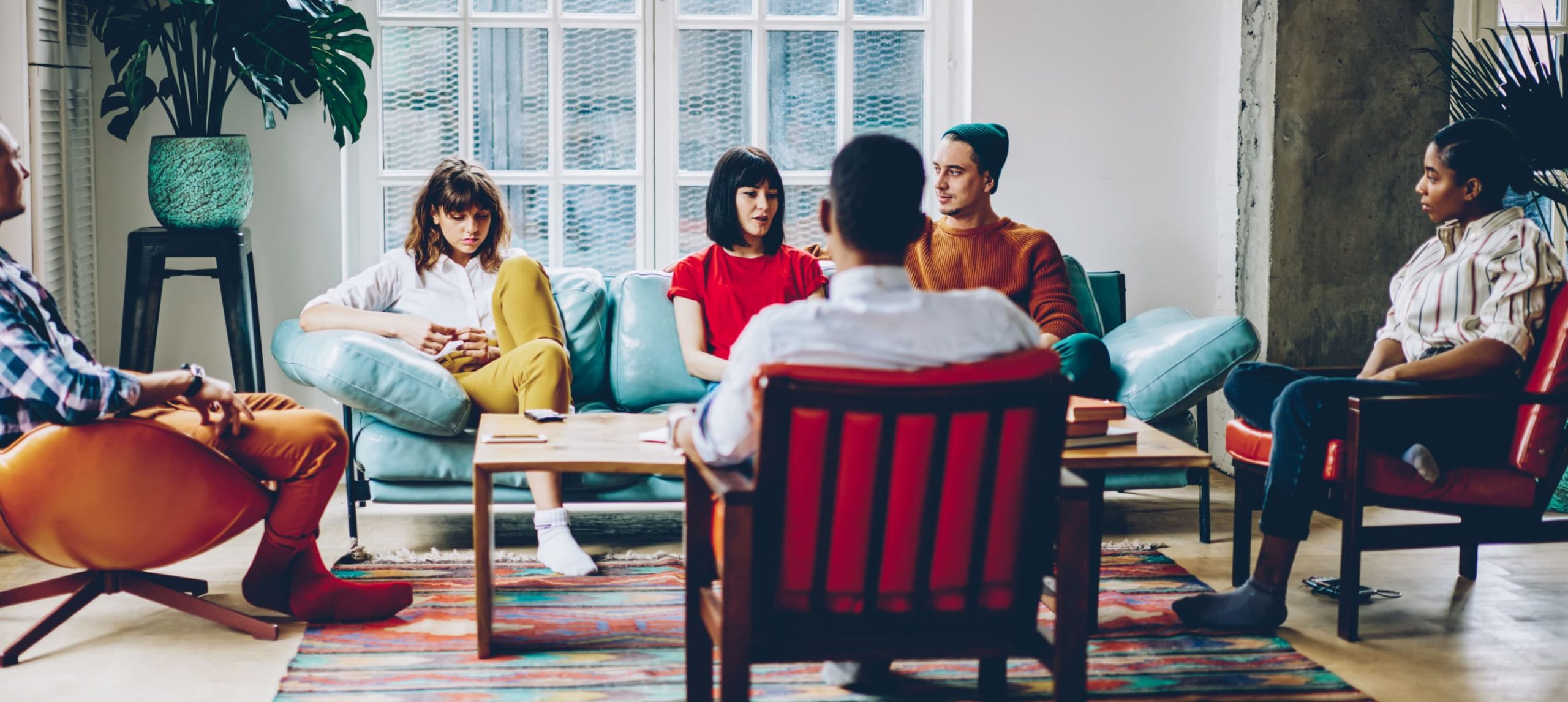 A group of young travelers talking in the common area of a hostel.