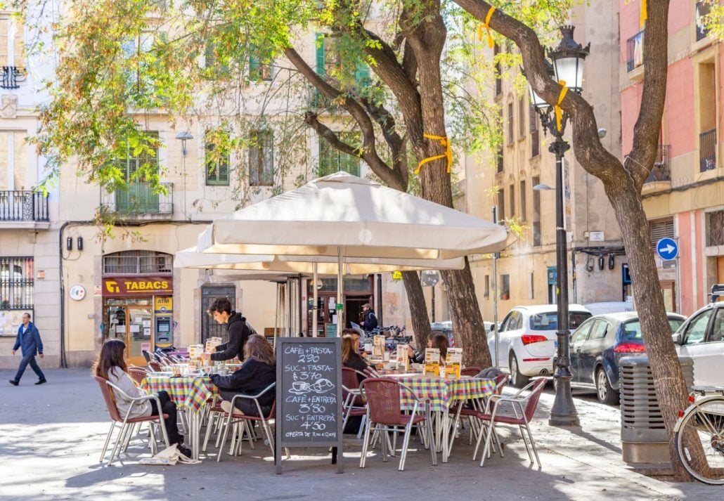 Bar terrace in Plaça de la Vila, in Gracia quarter, Barcelona. People having a drink and eating tapas on a sunny and relaxed morning.