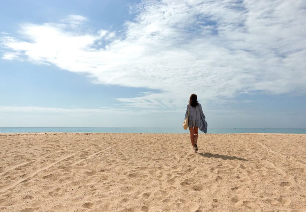 a woman walking on a sandy beach