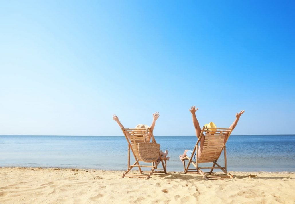 a couple sitting on beach chairs on a sandy beach