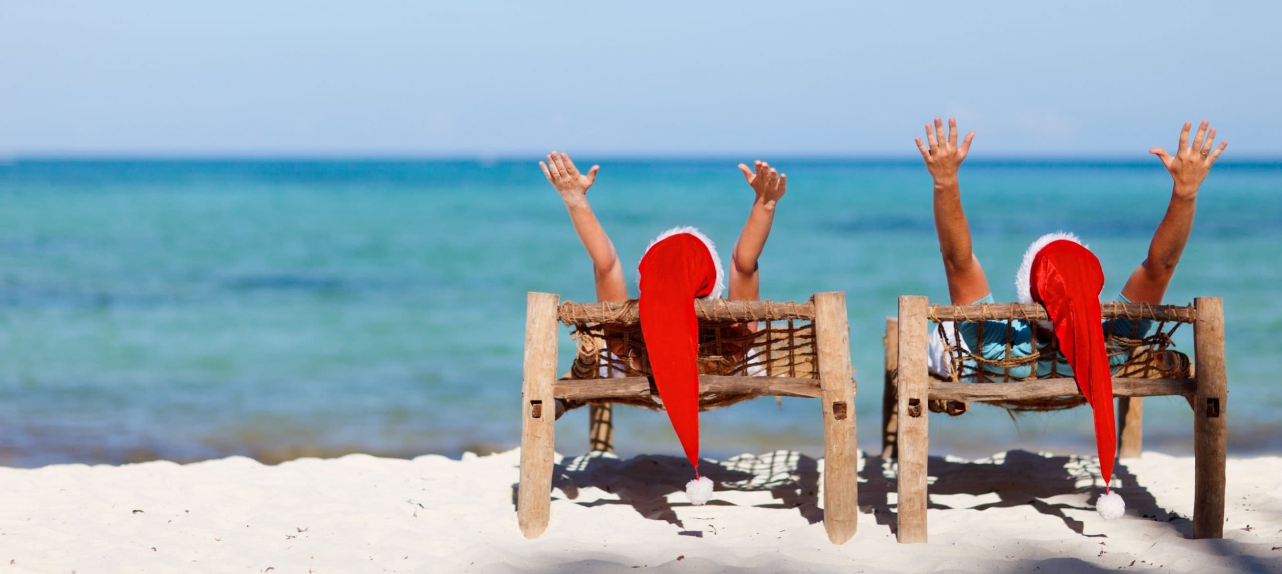 a couple laying on the beach with Santa Claus hats on