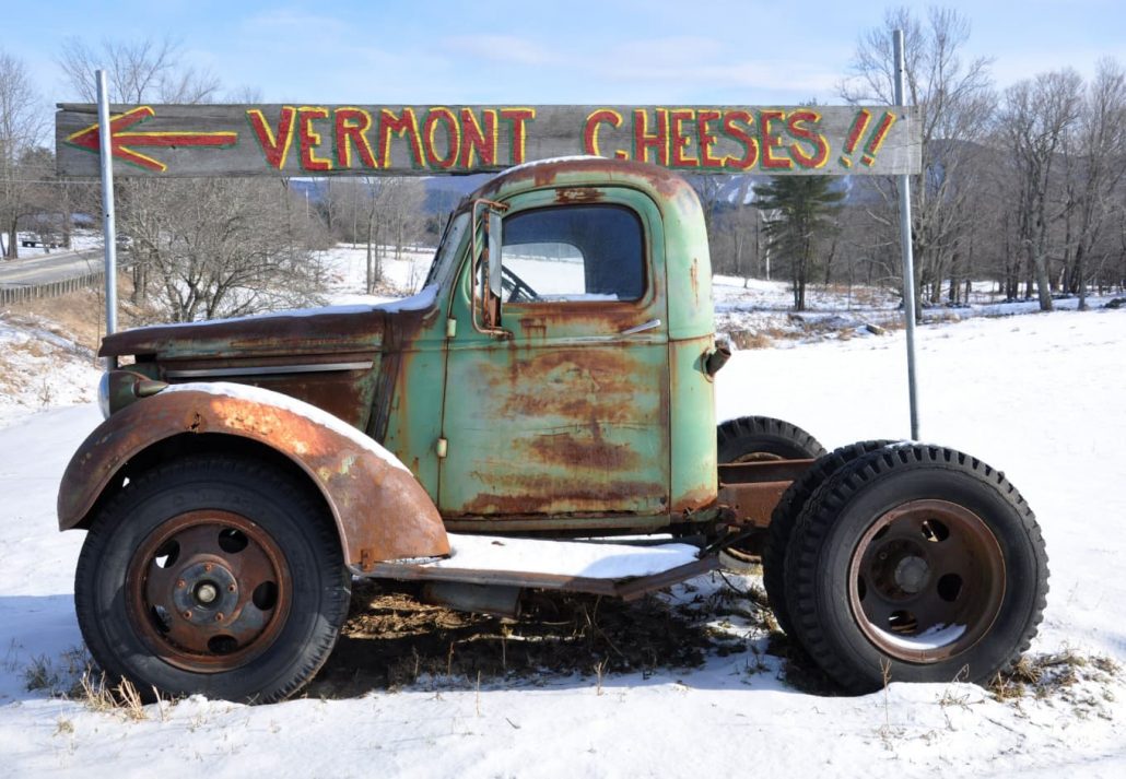 an old rusty truck with a sign that says 'Vermont Cheeses'