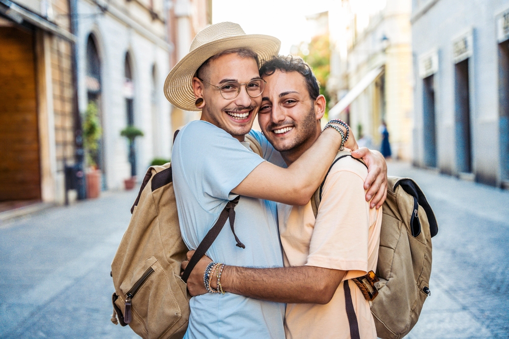 GayCoupleHuggingTogetherStandingInCityStreet-Homosexual | CuddlyNest Travel Blog