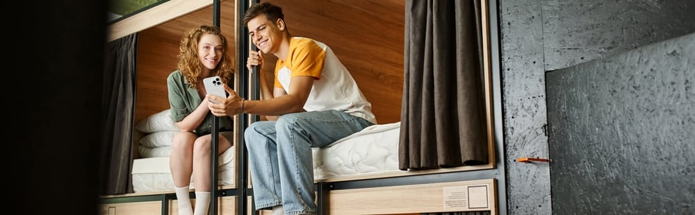 CarefreeYouthfulWomanShowingSmartphoneToBoyfriendOnDouble-deckerBeds | CuddlyNest Travel Blog
