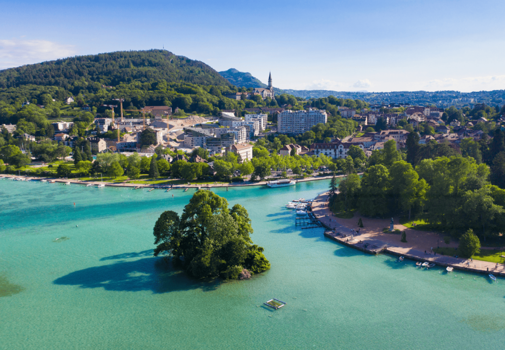 best european travel dupes for overrated spots Aerial view of Annecy lake waterfront in France