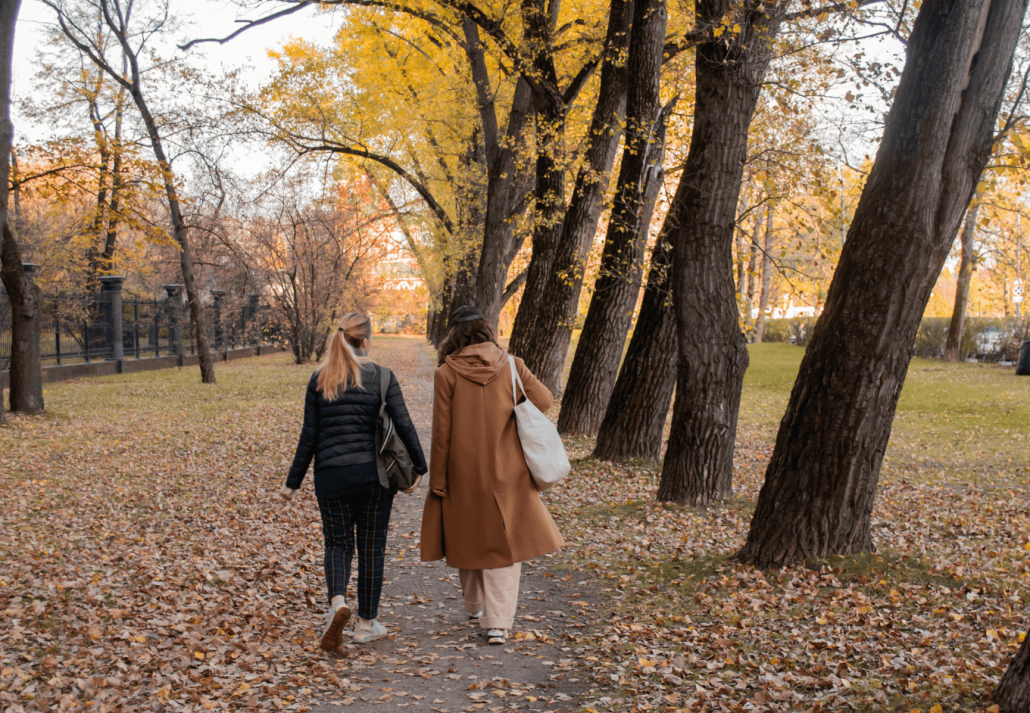 where to experience sleep tourism in new york city Two friends walk together side by side along a path through autumn city park. Beauty of fall season