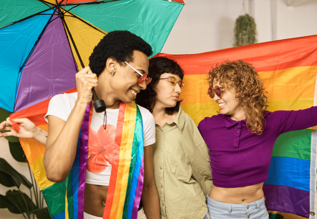 Multiethnic lgbt friends celebrating with rainbow umbrella and flag