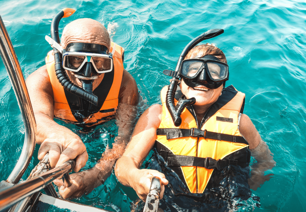 Retired couple taking happy selfie in tropical sea excursion with life vests and snorkel masks
