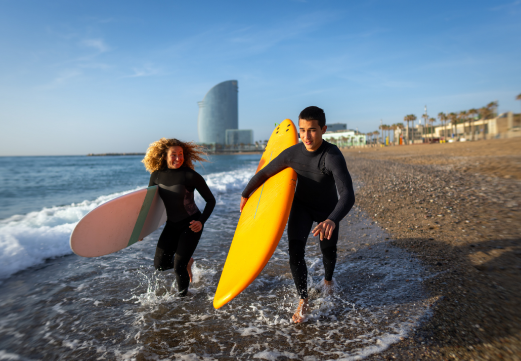 Beautiful happy surfer couple having fun on the beach, running with surfboard to the waves