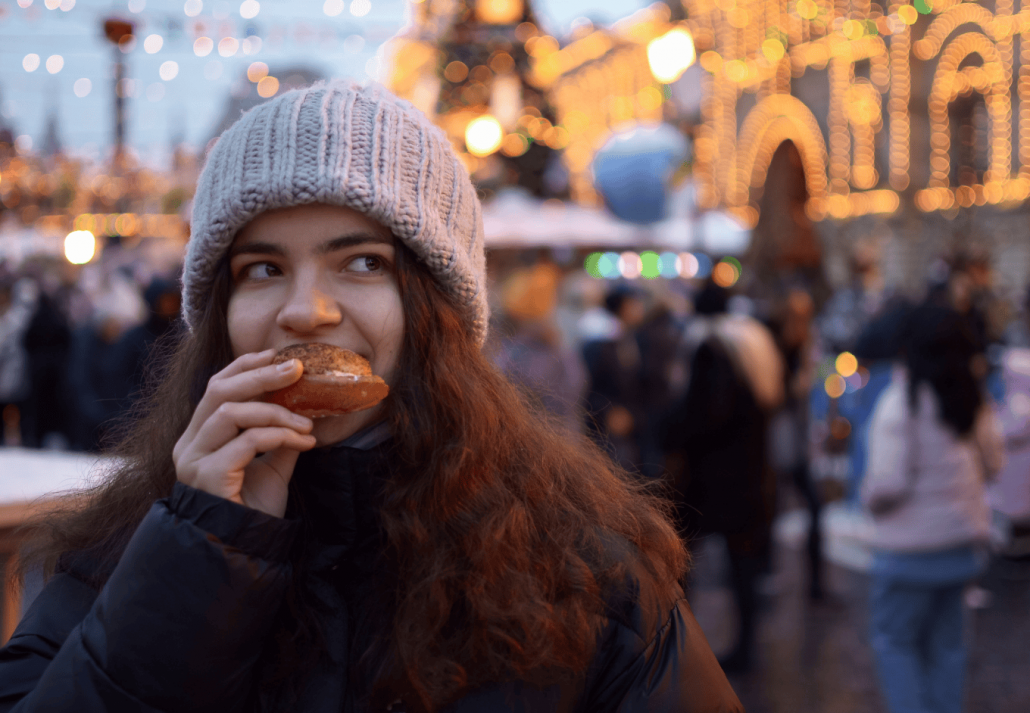 Close-up of a young woman who eats a cinnamon roll at a New York Christmas Market