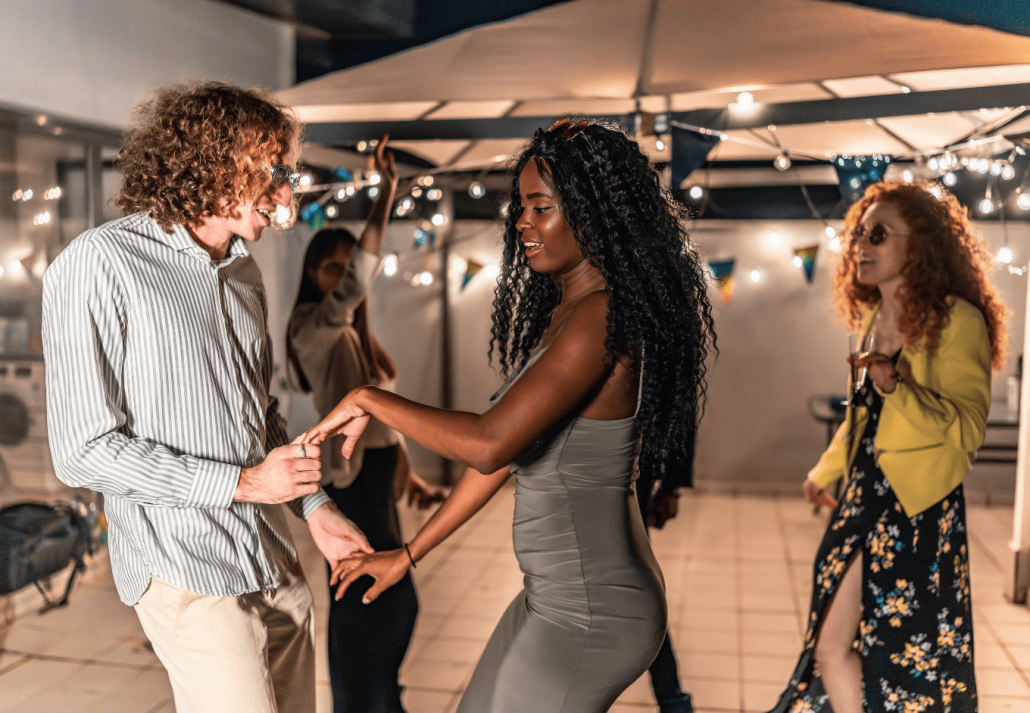 Multi-ethnic friends dancing holding hands latin music at night party