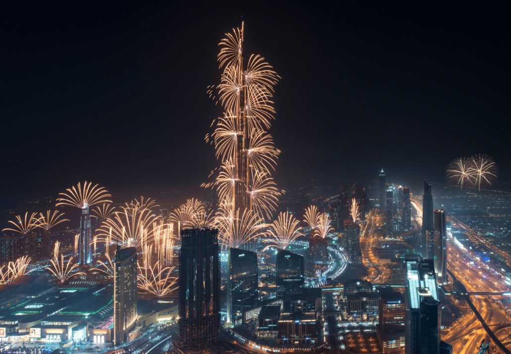 Cityscape of Dubai, United Arab Emirates at night, with fireworks and illuminated skyscrapers.