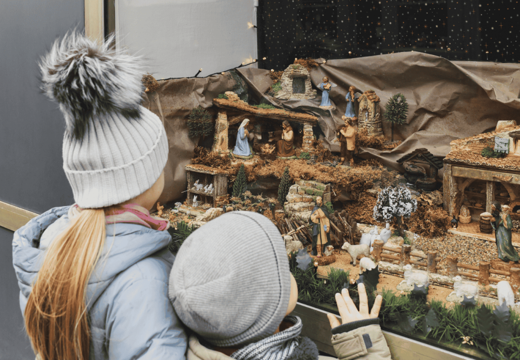 
The kids looking at a Christmas nativity scene with baby Jesus Creche Figurines in a shop window